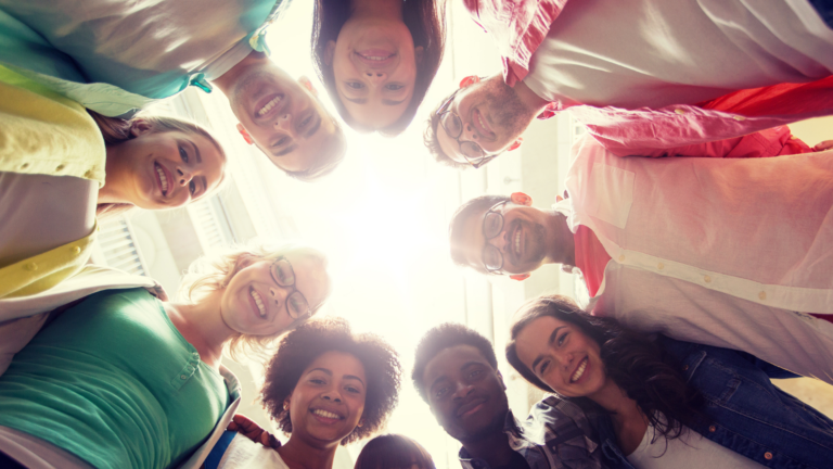 group of students in a circle looking down at camera